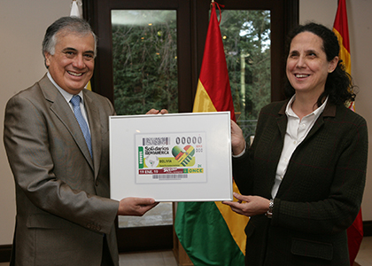 La directora de RRII de la ONCE, Ana Peláez, entrega el cupón enmarcado al embajador de Bolivia en España, Jorge Ramiro Tapia Sáinz