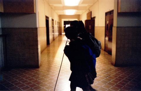 Dos niñas, una de ellas con bastón blanco, caminan por los pasillos de un centro educativo