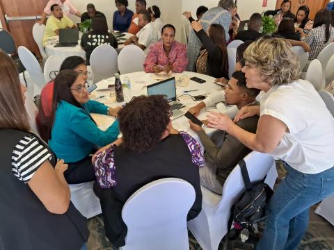 Varias personas sentadas en una mesa redonda interactúan con la voluntaria de FOAL